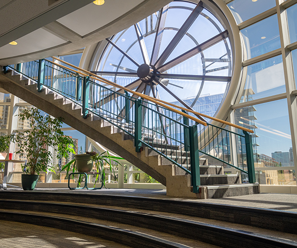 A photograph of an open staircase in front of a glass window with an embedded clock