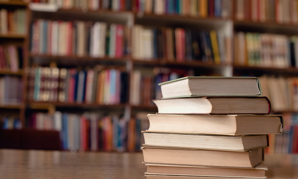 A stack of books on top of a table in a library