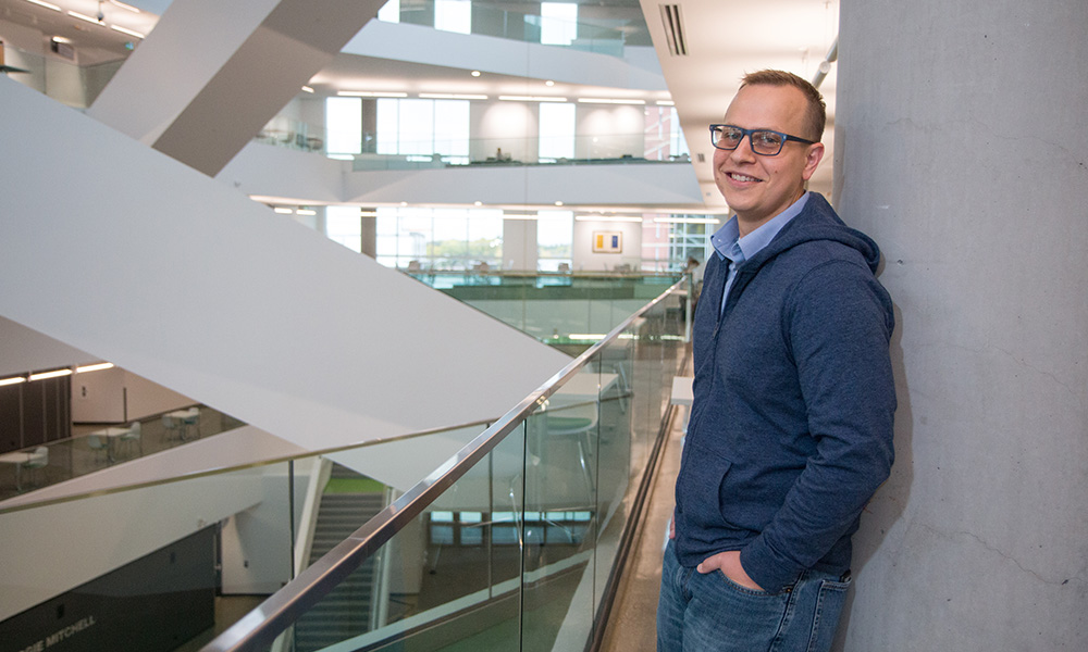 A man leans against a pillar in a large building