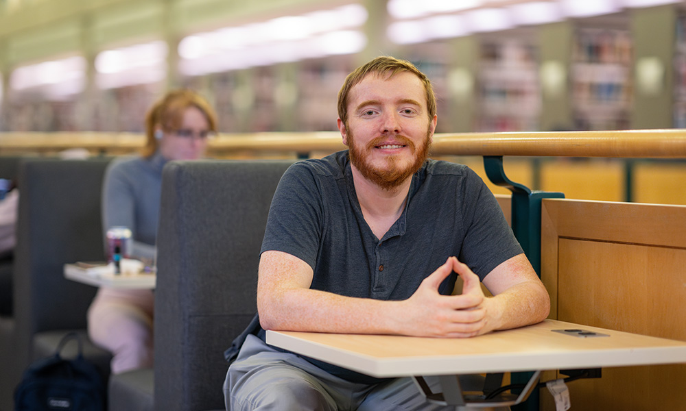 A student sitting at a table in a library