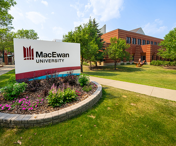 an outdoor shot of a brick building in the background with a planter and building sign in the foreground