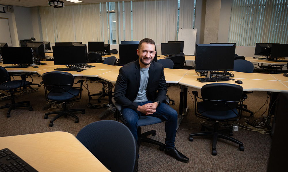 Cody Esih sits on a chair in a computer lab
