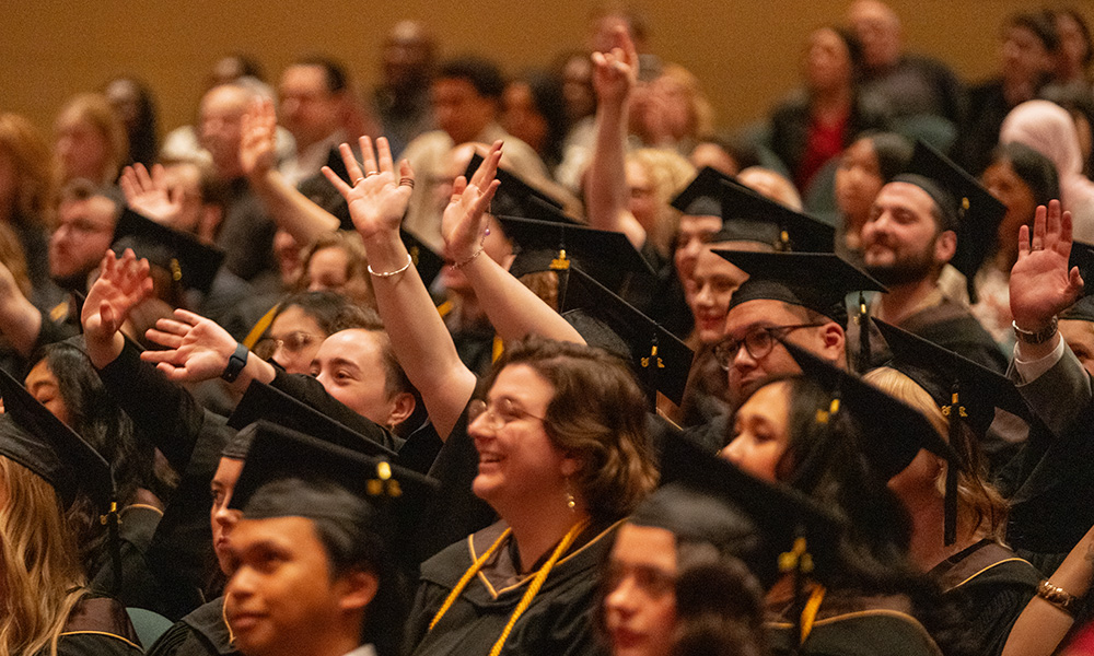 Graduates wave at clap for faculty members during convocation
