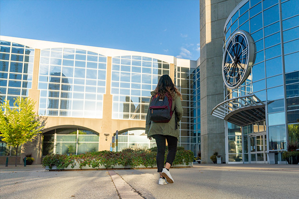 female student walking to the front doors of MacEwan University