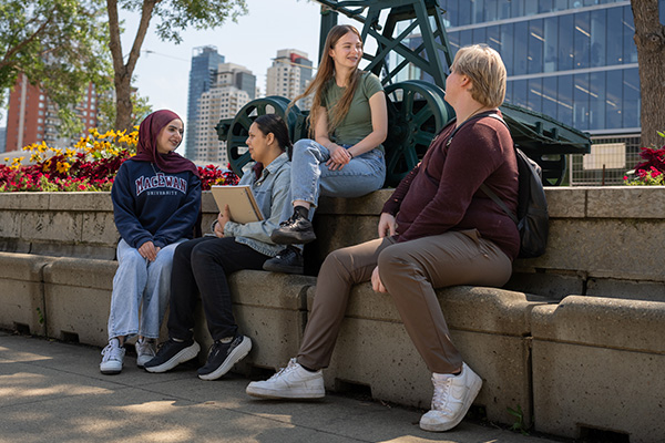 students sitting outside in the summer with flowers and a city background
