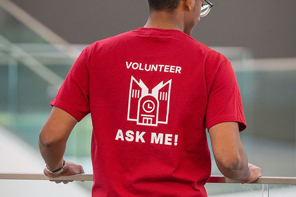 back of a red t-shirt that says volunteer ask me on it