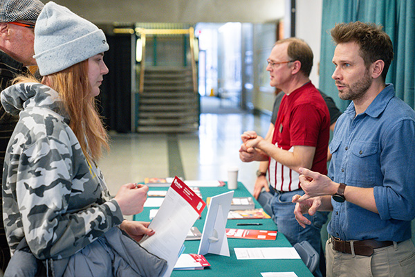 student speaking to a man at a program booth