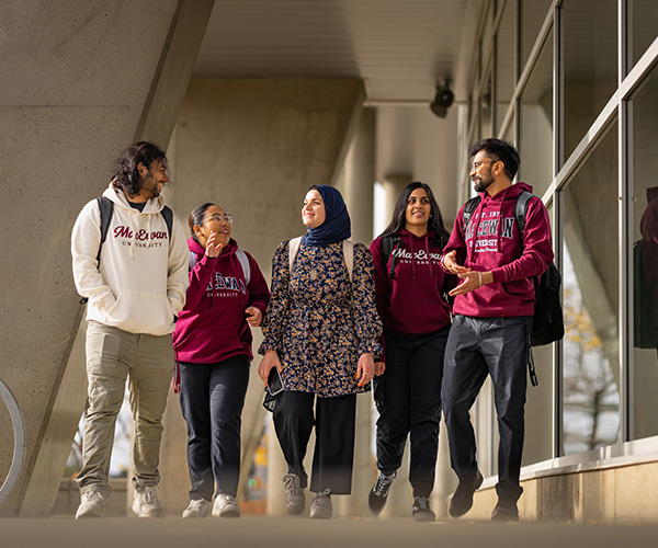 MacEwan students walking together on campus, wearing MacEwan University sweatshirts and talking between classes.