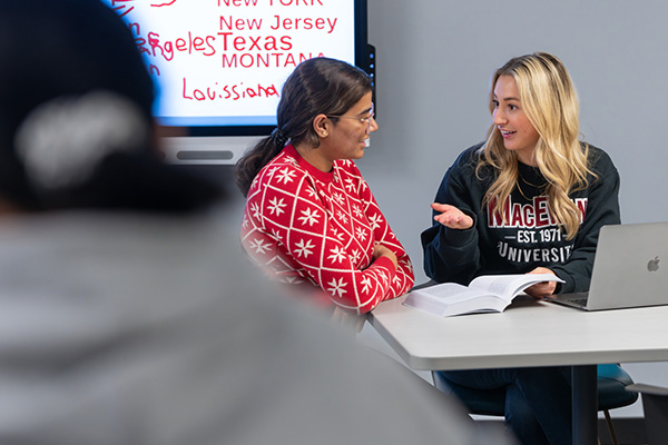 two female students talking over a book