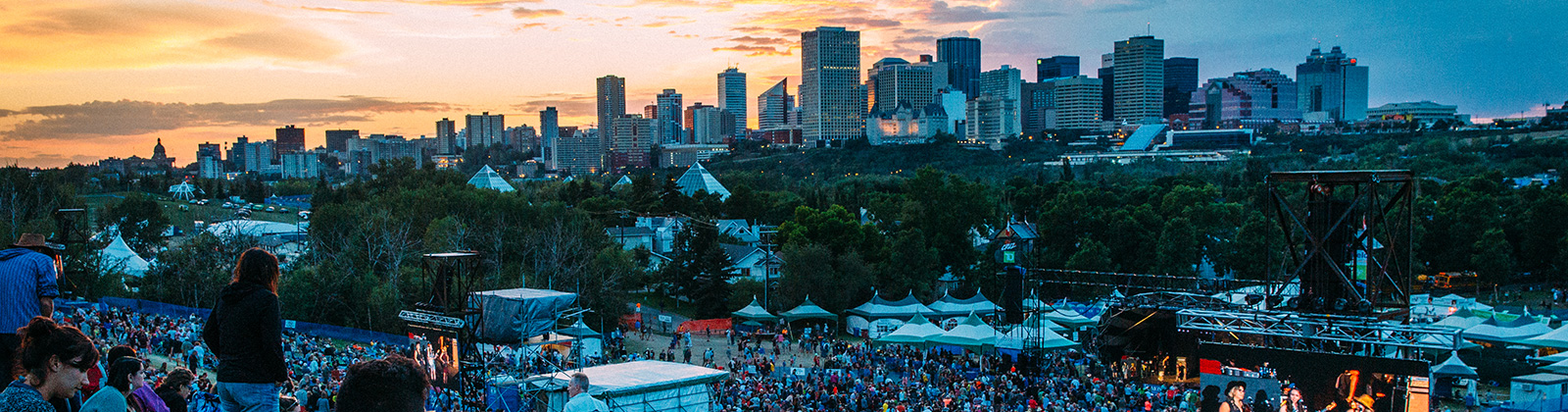 a view of the edmonton skyline at sunset above the crowd and tents at the edmonton folk festival